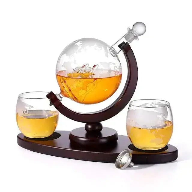 Whiskey decanter globe wine aerator glass set with sailboat and skull motifs on a wood stand.