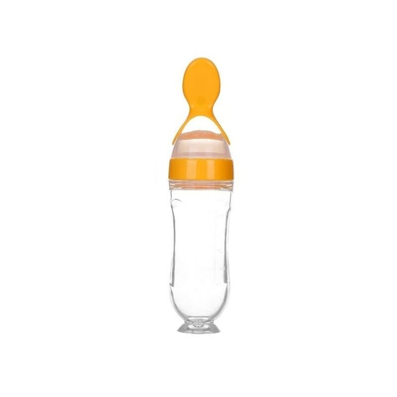 Baby squeezing feeding bottle with attached orange silicone spoon.