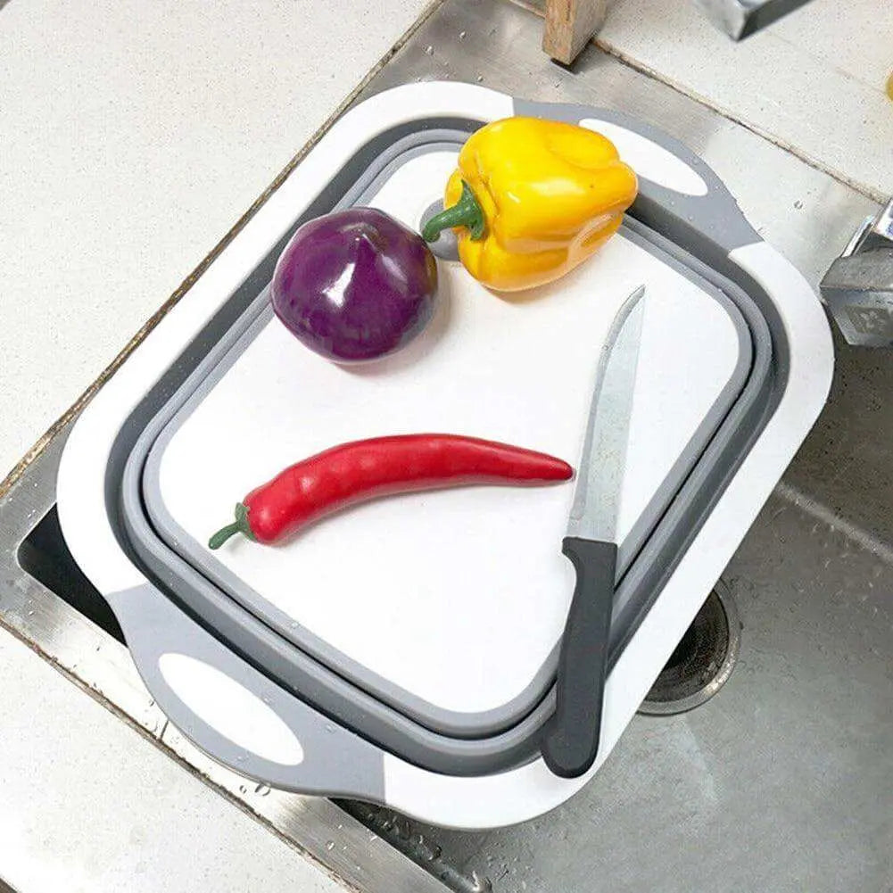 Folding chopping board with knife and vegetables, placed over a kitchen sink.
